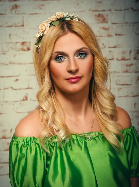 魅力十足的女孩，在一条绿色的连衣裙上砖的背景墙上的肖像 — 图库照片
