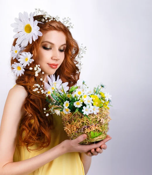 Menina com margaridas no cabelo segurando um buquê de margaridas — Fotografia de Stock