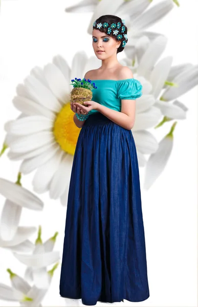 Menina camponesa.Menina da moda com uma maquiagem azul-turquesa brilhante e flores em seu cabelo e mão. estilo rústico. margaridas em um contexto — Fotografia de Stock