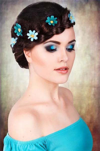 Retrato de moda de uma menina com uma maquiagem azul-turquesa brilhante e flores em seu cabelo. pele limpa . — Fotografia de Stock