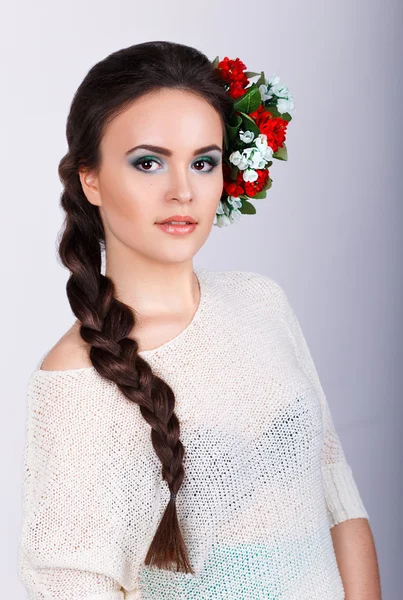 Meisje met lange donkere plait en bloemen in haar haar. Studio portret van een mooie brunette meisje — Stockfoto