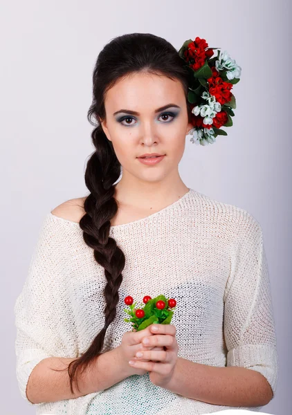 Mädchen mit langen dunklen Zöpfen und Blumen im Haar.Studioporträt eines schönen brünetten Mädchens — Stockfoto