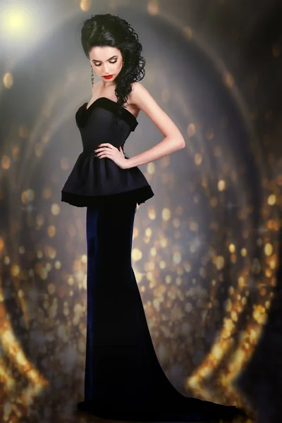 Elegantní žena ve večerních šatech na zlaté pozadí — Stock fotografie