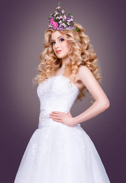 A menyasszony egy csodálatos fehér esküvői ruha a szürke background.beauty portré egy szőke, a tökéletes smink és virág koronát a fején. — Stock Fotó