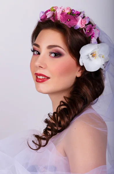 Bukett av vackra blommor på damens head.brunette i en tyll klänning. Mode Art.Hairstyle med flowers.girl med orkidéer blomma i håret. — Stockfoto