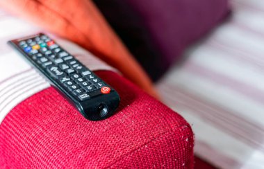 Kırmızı bir kanepede tozlu televizyon kumandası var. Kanepeye pamuk koyun. Sabit bir hayat ve ev eğlencesi. Uzaktan kumandaya seçmeli odaklan