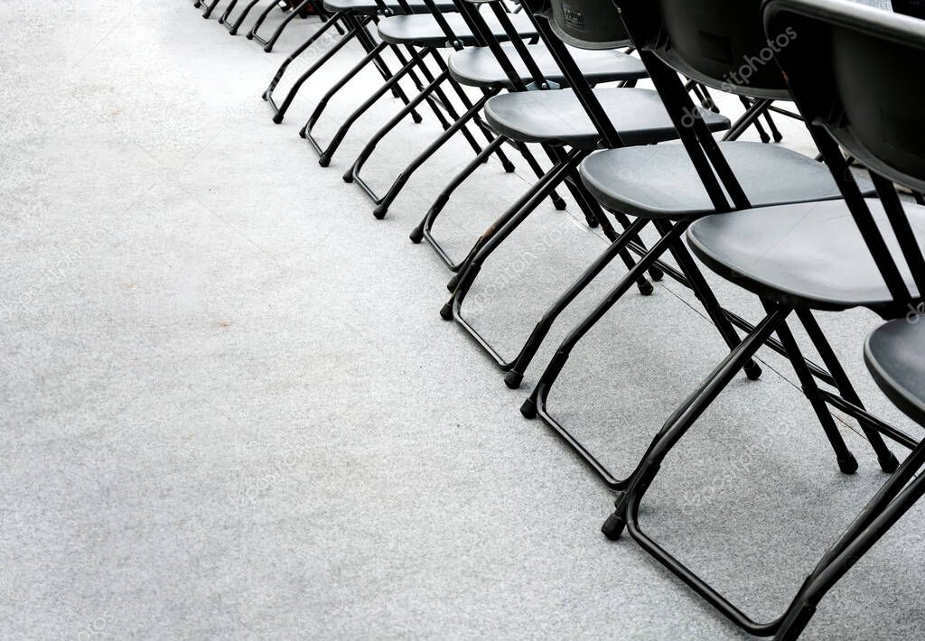 a group of empty folding chairs arranged in a row in a conference room. Copy space. Gray background