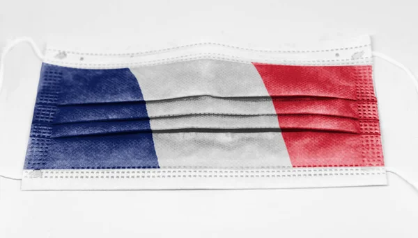 使い捨ての外科用マスクにフランスの国旗が印刷されている コロナウイルスは19種のパンデミックの予防と保護に成功した — ストック写真
