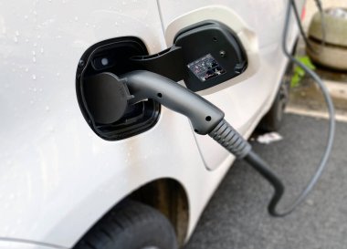 Şehrin caddesindeki şarj istasyonuna bağlı bir elektrikli arabayı şarj etmek. Sürdürülebilir ve ekolojik hareketlilik kavramı. Sıfır kirletici emisyon ile hareket