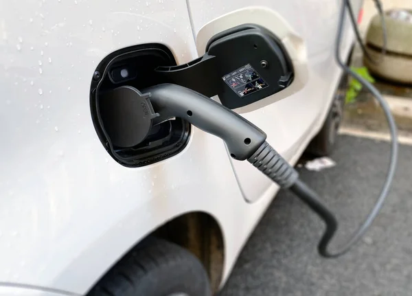 Recharging an electric car with a plug connected to the charging station on a city street. Concept of sustainable and ecological mobility. Mobility with zero polluting emissions