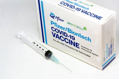 New York, 5 Şubat 2021: Beyaz arka planda izole edilmiş Pfizer BioNTech Covid-19 aşı kutusunun yanında bir şırınga. Sağlık ve Önleme.