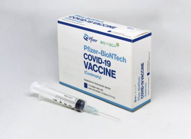 New York, 5 Şubat 2021: Beyaz arka planda izole edilmiş Pfizer BioNTech Covid-19 aşı kutusunun yanında bir şırınga. Sağlık ve Önleme.