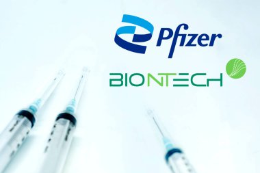 New York USA, 10 Şubat 2021: Pfizer Biyoteknik logosunun yanındaki üç şırınga beyaz arka planda izole edilmiş. Sağlık ve Önleme. Pfizer Biontech Covid-19 aşısı.
