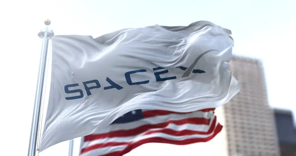 Hawthorne, CA, ABD, 9 Mart 2021: SpaceX logosu rüzgarda dalgalanan beyaz bayrak, arka planda Amerikan yıldızları ve çizgili bayrak. Havacılık teknolojisi ve uzay görevleri.