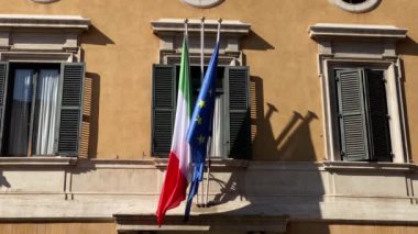 İtalya ve Avrupa 'nın bayrakları hafif bir rüzgarda dalgalanıyor. İtalyan ulusal bayrağı ve Avrupa Birliği. Kamu binası cephesi.