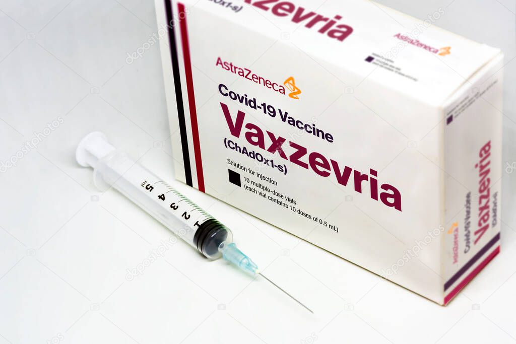 Cambridge, UK, march 30 2021: A syringe next to the Vaxzevria Covid-19 vaccine (previously Astrazeneca covid-19 vaccine) box isolated on a white background. Health and prevention.