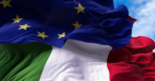 在风中飘扬的意大利国旗和欧盟国旗在前景上模糊不清 政治和金融 意大利是欧洲联盟的成员国 — 图库照片