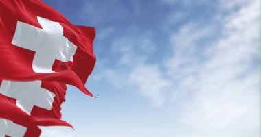 Açık bir günde rüzgarda dalgalanan İsviçre ulusal bayraklarının yakın çekimi. Ortasında beyaz haç olan kırmızı arka plan. Kusursuz 3 boyutlu animasyon. Yavaş çekim döngüsü. Seçici odak