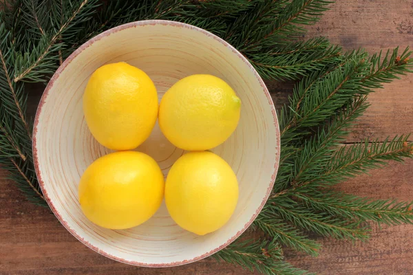 크리스마스 나뭇가지로 그릇에 레몬을 얹는다 감귤류의 과일들이 배경에 있습니다 바닥에 — 스톡 사진
