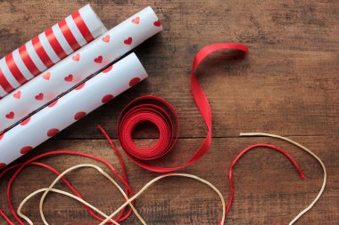 Tahta masada kırmızı ve beyaz ambalaj kağıtları ve kurdeleler. Tatil geçmişi. Üst görünüm, alanı kopyala