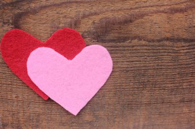 Ahşap arka planda keçeli kumaştan yapılmış kırmızı ve pembe kalpler. Sevgililer Günü kompozisyonu düzdü. Boşluğu kopyala