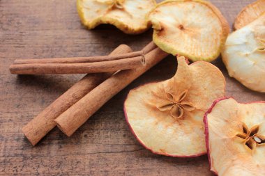 Kurutulmuş elma halkaları ve ahşap arka planda tarçın çubukları. Üst Manzara. Kırsal tarzda. Seçici odak