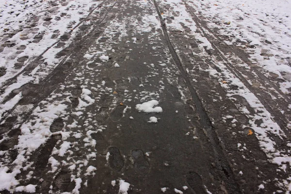 閉じる車の痕跡や雪の上の足跡とぬかるんだ道路のアップ 選択的焦点 — ストック写真