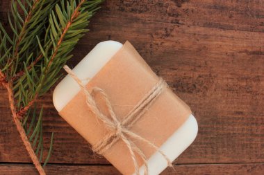 El yapımı doğal kozalaklı sabun çubuğu el yapımı kağıt ve ahşap masa üzerinde köknar ağacı dalı. Çevre dostu Noel hediyesi.