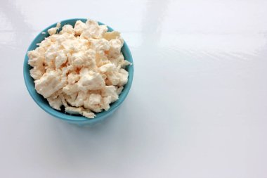 Mavi kasede beyaz masada süzme peynir. Ev yapımı süt ricotta. Üst Manzara. Boşluğu kopyala