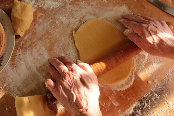 Overview of elderly woman hands rolling out the dough with a rolling pin.Overview of elderly woman hands rolling out the dough with a rolling pin.