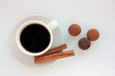 Beyaz arka planda çikolatalı trüf mantarlı ve tarçınlı bir fincan kahve. Üst görünüm, alanı kopyala