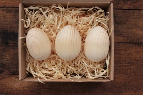Blank wooden eggs for painting or decoupage in gift box. Easter eggs in a basket on wood table. Top view