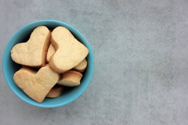Kalp şeklinde kurabiyeler ızgara beton arka planda mavi kasede. Genel görünüm, boşluğu kopyala