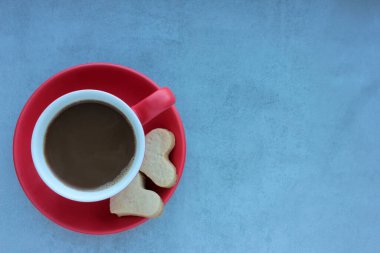 Gri beton arka planda kırmızı kahve ve kalp şeklinde kurabiyeler. Düz yerde yemek vardı. Boşluğu kopyala, 
