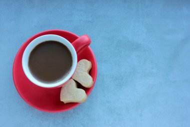 Gri beton arka planda kırmızı kahve ve kalp şeklinde kurabiyeler. Düz yerde yemek vardı. Boşluğu kopyala, 