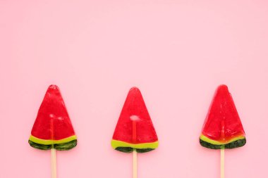 Pembe arka planda karpuz buzlu dondurma. Parlak yaz geçmişi. Karpuz şeklinde lolipop. Çubukta şeker. Üst görünüm, alanı kopyala
