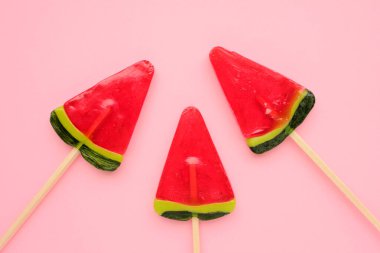 Pembe arka planda karpuz buzlu dondurma. Parlak yaz geçmişi. Karpuz şeklinde lolipop. Çubukta şeker. Üst görünüm, alanı kopyala