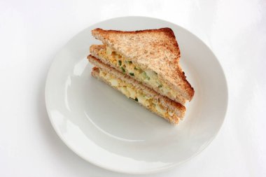 Yumurtalı sandviç, kepekli tost ekmeği ve beyaz arka planda mikroyeşillikler. Sağlıklı gıda konsepti