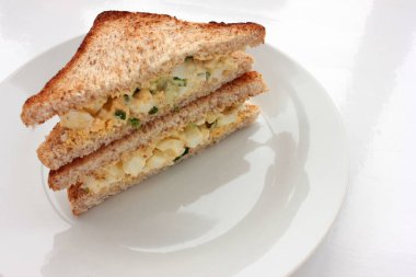 Yumurtalı sandviç, kepekli tost ekmeği ve beyaz arka planda mikroyeşillikler. Sağlıklı gıda konsepti