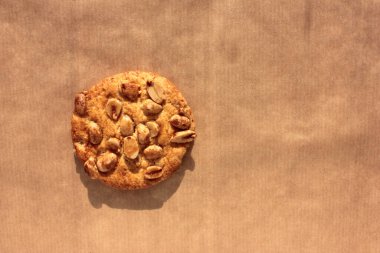 Kraft kağıdında tek fıstıklı kurabiye. Fotokopi alanı olan kahverengi arkaplanlı ev yapımı hamur işlerinin yakın çekimi