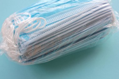 Mavi arka planda yeni koruyucu cerrahi maske yığını. İnsani yardım veya tıbbi malzeme konsepti. Üst görünüm