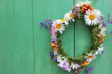 Çiçek kapılı çelenk. Kırsal ahşap arka planda kopyalanmış yaz ortası çiçeği tacı. DIY çiçek çelengi. Yaz ortası rüya süslemesi
