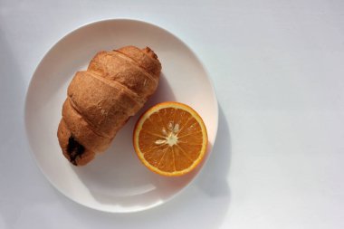 Sağlıklı kahvaltı, turuncu ve beyaz arka planda kruvasan. Düz kompozisyon. Boşluğu kopyala