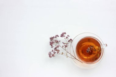Bir fincan bitkisel kekik çayı ve beyaz masa arkaplanında kuru marjoram çiçekleri ve fotokopi alanı. Üst Manzara. Düz konum