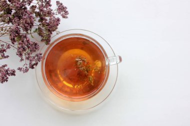 Bir fincan bitkisel kekik çayı ve beyaz masa arkaplanında kuru marjoram çiçekleri ve fotokopi alanı. Üst Manzara. Düz konum