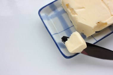 Beyaz masa arkasındaki mavi tabakta taze tereyağı. Genel bakış. Sağlıklı kahvaltı malzemesi.