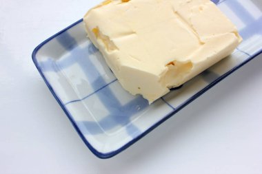 Beyaz masa arkasındaki mavi tabakta taze tereyağı. Genel bakış. Sağlıklı kahvaltı malzemesi.