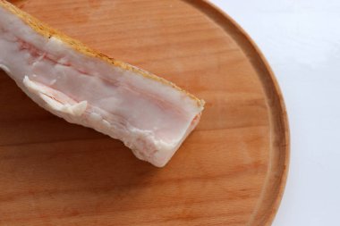 Beyaz masa arkasındaki tahta kesme tahtasının üzerinde dilimlenmiş domuz yağı. Üst görünüm