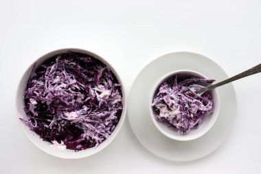 Beyaz masa arka planında kırmızı lahana kabından ev yapımı kremalı lahana salatası. Üst görünüm, boşluğu kopyala. Mayonez soslu taze sebze salatası. Düz yerde yemek vardı. Sağlıklı yeme kavramı