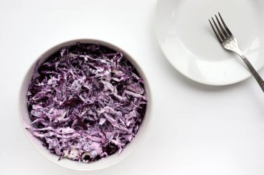 Beyaz masa arka planında kırmızı lahana kabından ev yapımı kremalı lahana salatası. Üst görünüm, boşluğu kopyala. Mayonez soslu taze sebze salatası. Düz yerde yemek vardı. Sağlıklı yeme kavramı